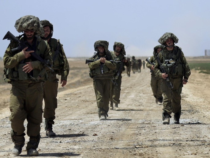 Israeli reserve soldiers return to Israel after fighting in Khan Younis in the Gaza Strip, while walking on a road near the Israel Gaza border on Wednesday, July 30, 2014. On Wednesday, Israeli aircraft struck dozens of Gaza sites, including five mosques it said were being used by militants, while several other areas came under tank fire. (AP Photo/Tsafrir Abayov)