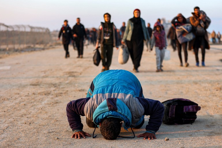 A boy prostrates in a prayer of gratitude as people walk along Gaza's coastal al-Rashid Street to cross the Netzarim corridor from the southern Gaza Strip into the north on January 27, 2025. Displaced Palestinians began returning to northern Gaza on January 27, an official at the territory's Hamas-run Interior Ministry told AFP, after a breakthrough in negotiations between Hamas and Israel. (Photo by Omar AL-QATTAA / AFP)