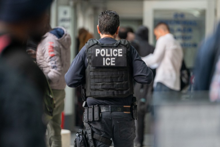 NEW YORK, NEW YORK - JUNE 6: An ICE agent monitors hundreds of asylum seekers being processed upon entering the Jacob K. Javits Federal Building on June 6, 2023 in New York City. New York City has provided sanctuary to over 46,000 asylum seekers since 2013, when the city passed a law prohibiting city agencies from cooperating with federal immigration enforcement agencies unless there is a warrant for the person's arrest. David Dee Delgado/Getty Images/AFP (Photo by David Dee Delgado / GETTY IMAGES NORTH AMERICA / Getty Images via AFP)