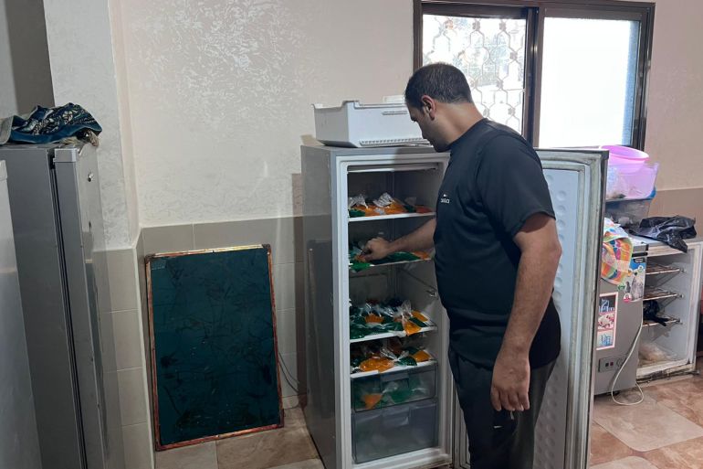 المجدلاوي أثناء عمله في تعبئة ثلاجته بأكياس البراد لتبريدها (الجزيرة)