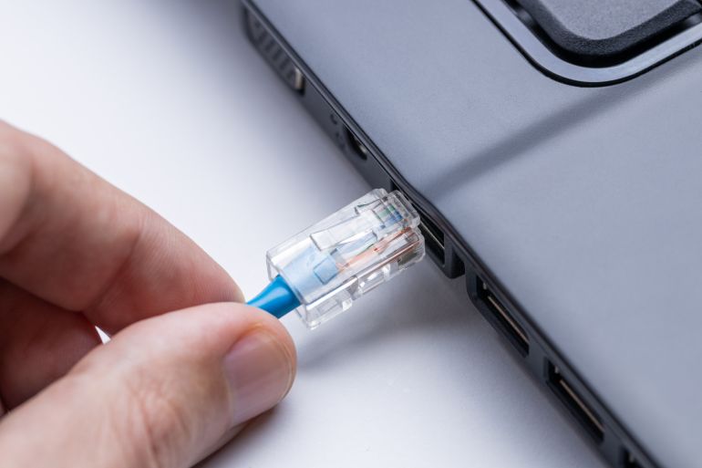 person plugging internet ethernet cable to laptop pc. online and network access conceptual. internet connection problem conceptual.