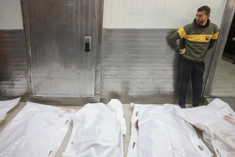 A man stands next to white body bags while attending the funeral of Palestinians killed on December 3, by an Israeli strike, at Nasser Hospital in Khan Yunis, southern Gaza Strip on December 4, 2025.