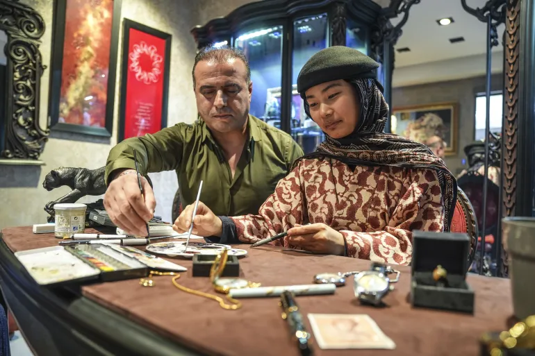 من طوكيو إلى إسطنبول، انتقلت الطالبة اليابانية شينكو شيراكاوا برحلة دراسية وثقافية قادتها لدراسة الفنون التركية التقليدية في جامعة معمار سنان للفنون الجميلة، حيث تعكس أعمالها تلاقي الفن الياباني مع الزخرفة الإسلامية. وفي ورشة صغيرة بإسطنبول، تنجز شيراكاوا (27 عاما)، التي اختارت اسم "شولة" بعد اعتناقها الإسلام، أعمالا فنية دقيقة تمزج بين ثقافتين متباعدتين جغرافيا ومتقاربتين روحيا، ضمن تجربة فنية تعتمد الرسم المتناهي الدقة وتستلهم من العمارة والزخارف الإسلامية التركية. وتعتمد في أعمالها على تقنية الرسم الدقيق (الميكرو أرت)، حيث توظف الزخارف الهندسية اليابانية إلى جانب أنماط العمارة السلجوقية التي تعكس مفهوم اللانهاية في تجربة تجمع بين ثقافتين عريقتين ضمن قالب إبداعي معاصر. ( Ağıt Erdi Ulukaya - وكالة الأناضول )