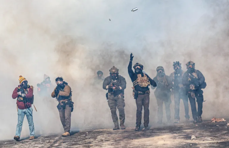 A federal agent lobs a teargas canister towards protesters as agents advance through clouds of tear gas during clashes following the fatal shooting of a protester earlier in the day, on January 24, 2026 in Minneapolis, Minnesota.