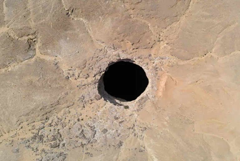 An aerial view taken on June 6, 2021 shows the Well of Barhout known as the "Well of Hell" in the desert of Yemen's Al-Mahra province. - Closer to the border with Oman than to the capital Sanaa 1,300 kilometres (800 miles) away, the giant hole in the desert of Al-Mahra province is 30 metres wide and thought to be anywhere between 100 and 250 metres deep. Local folklore says it was created as a prison for the demons -- a reputation bolstered by the foul odours rising from its depths. (Photo by - / AFP) (Photo by -/AFP via Getty Images)