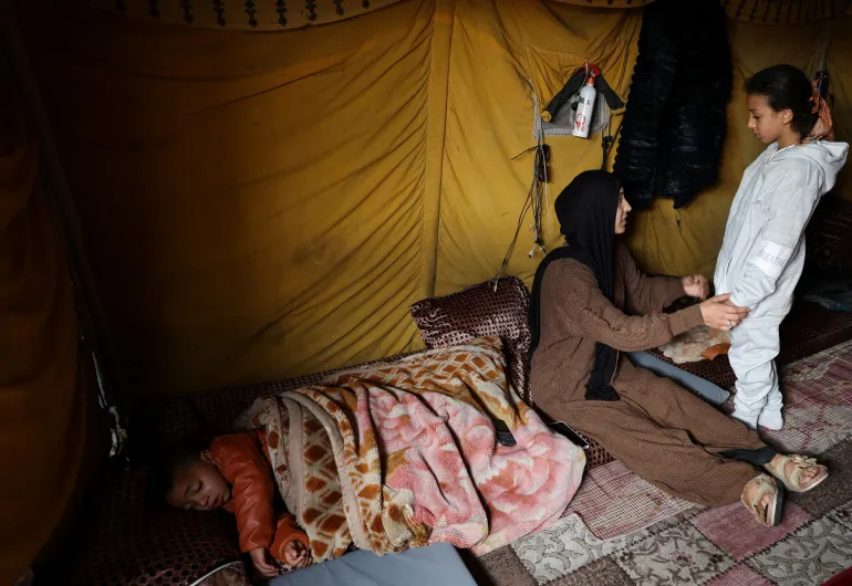 غزة/القاهرة 6 فبراير شباط (رويترز) - تترقب اعتدال ريان بشوق لحظة لم شمل أسرتها في قطاع غزة منذ قرابة عامين، وتقول إنها لا تزال تشعر بالحنين إلى عائلتها ووطنها رغم الدمار الواسع الذي خلفته الحرب التي دارت رحاها على مدى نحو عامين في القطاع الفلسطيني. Palestinian mother of three, Eatedal Rayyan, 29, sits in a tent set up inside her war-damaged home following her return from medical treatment in Egypt, after nearly two years away, in northern Gaza Strip, February 6, 2026. REUTERS/Dawoud Abu Alkas