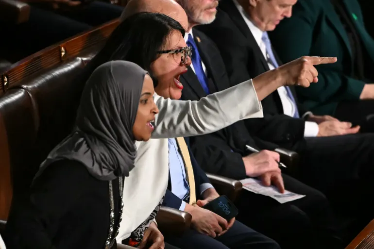 (L/R) US Representatives Ilhan Omar, Democrat from Minnesota, and Rashida Tlaib, Democrat from Michigan, shout as President Donald Trump delivers the State of the Union address in the House Chamber of the US Capitol in Washington, DC, on February 24, 2026. (Photo by ANDREW CABALLERO-REYNOLDS / AFP)