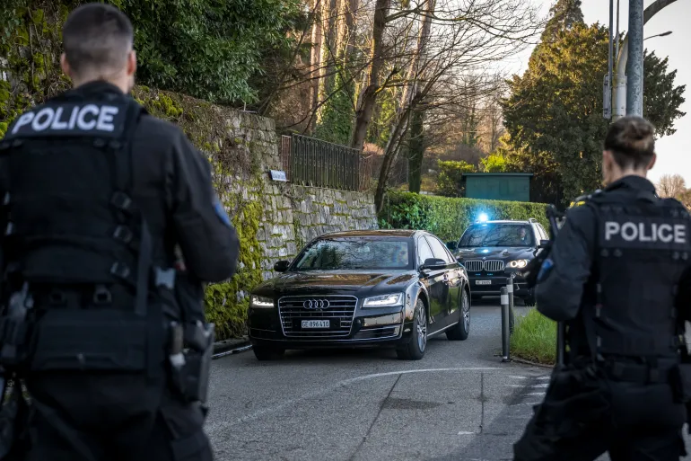 Police officers stand by as a convoy arrives at the Oman's ambassador residency for new round of talks between the United States and Iran to address Iran's nuclear program, in Geneva on February 26, 2026.