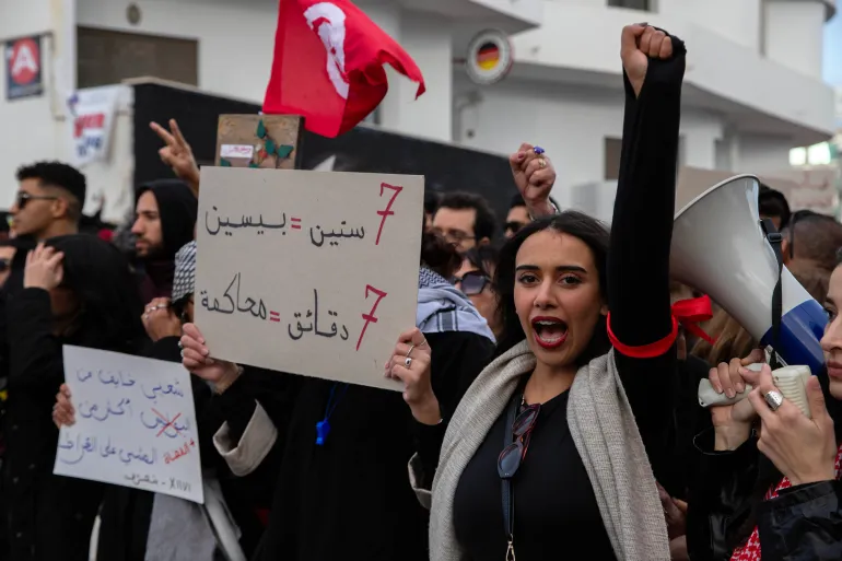 People take part in a protest against Tunisian president Kais Saied's rule and demanding the release of political prisoners in Tunis, Tunisia, Saturday, Nov. 22, 2025. Banner in Arabic reads "7 minutes = trial duration." (AP Photo/Anis Mili)
