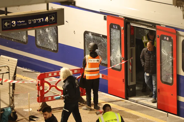 Israeli security forces and rescue workers gather at a train station that was hit by shrapnel after an Iranian strike in Tel Aviv on March 18, 2026. An Iranian missile barrage killed two people near Israel's commercial hub Tel Aviv, medics said on March 18, as the national railway company suspended operations due to shrapnel impact at a station in the city. Authorities reported that falling munitions had hit multiple sites in central Israel in the overnight barrage that triggered air raid sirens across the area, after another day of heavy Israeli bombardments in Iran and Lebanon. (Photo by JACK GUEZ / AFP) /