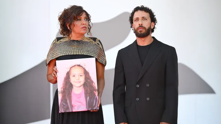 المخرجة التونسية كوثر بن هنية، والممثل الفلسطيني معتز مليس، يرفعان صورة الطفلة هند رجب عند وصولهم إلى العرض الأول لفيلم “صوت هند رجب” في مهرجان البندقية السينمائي