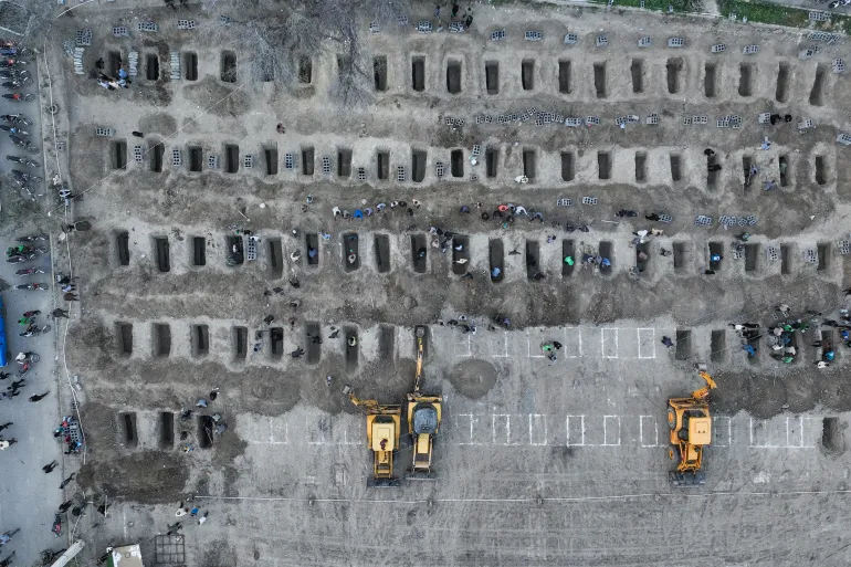TOPSHOT - In this aerial handout picture released by the Iranian Press Center, mourners dig graves during the funeral for children killed in a reported strike on a primary school in Iran’s Hormozgan province in Minab on March 3, 2026.