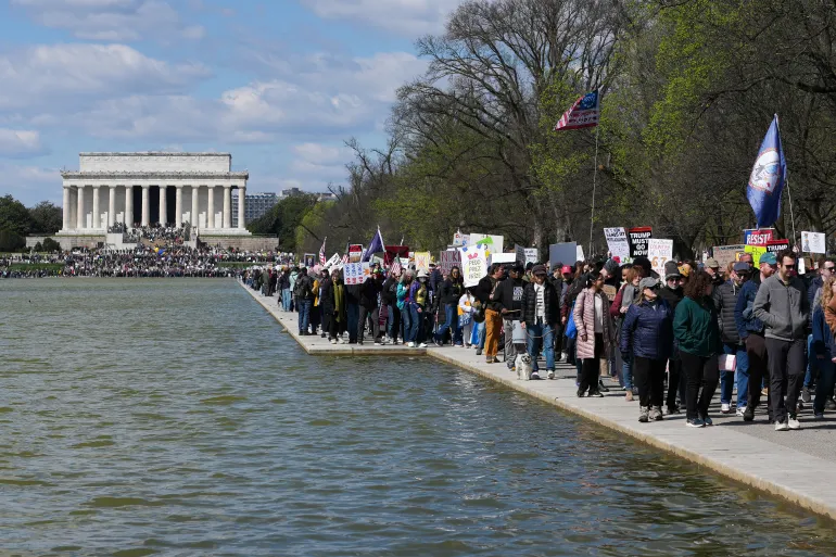 Demonstrators march along the reflecting pool near the Lincoln Memorial during the "No Kings" national day of protest in Washington, DC, on March 28, 2026.