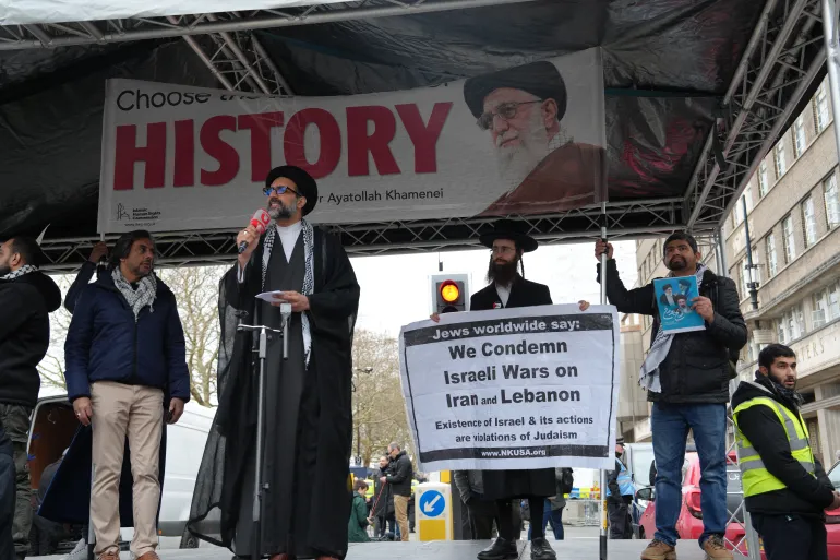حاخام يرفع لافتة خلف احد القيادات الايرانية يؤكد ادانة يهود ناطور كارتا للحرب على لبنان و إيران (المصدر الجزيرة )