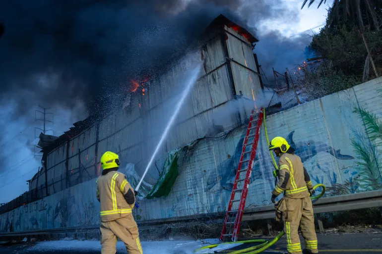 HOLON, ISRAEL - MARCH 13: Firefighters try to extinguish a fire at a warehouse that occurred amid a barrage of Iranian missiles on March 13, 2026 in Holon, Israel. The warehouse appeared to have been struck by parts of a projectile after its interception. Iran has continued firing waves of drones and missiles at Israel after the United States and Israel launched a joint attack on Iran early on February 28th. (Photo by Erik Marmor/Getty Images)