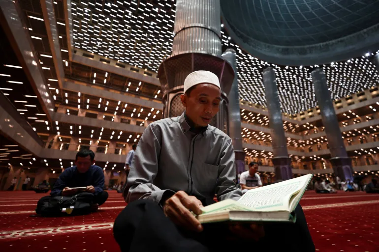 An Indonesian Muslim man reads the Koran while attending evening mass prayers during the first night of holy fasting month of Ramadan, at the Great Mosque of Istiqlal in Jakarta, Indonesia, February 18, 2026. REUTERS/Willy Kurniawan