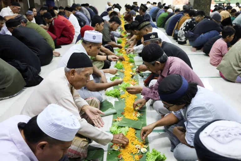Muslim men eat their iftar meals served on banana leaves, a practice locally called "Megibung", as they break their fast during the holy fasting month of Ramadan, at Baitul Makmur mosque in Denpasar, Bali, Indonesia, February 22, 2026. REUTERS/Johannes P. Christo