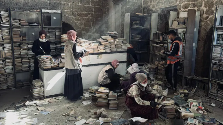 فلسطين - غزة-فريق تطوعي بإسعاف مخطوطات أثرية نادرة تم انتشالها من تحت أنقاض دائرة مخطوطات المسجد العمري - للحفاظ على ما تبقّى منها.- يسرى العكلوك -الجزيرة نت 11 أبريل 2026