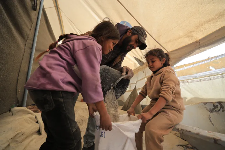 صورة رقم (7) تالا ورهف وهما يساعدان والدهم دون أدنى مقومات حماية خلال تعبئة الإسمنت لبيعه-إسراء الرّملي أبريل/2026