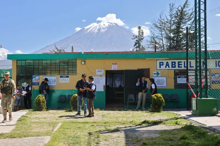Employees of the National Office of Electoral Processes (ONPE), observers of the European Union and a member of the armed forces are seen outside a polling station in the district of Chiguata, an agricultural area located some 25 kilometres from Arequipa, Peru on April 12, 2026, during general elections.