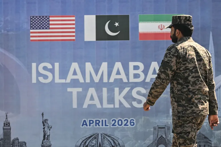 A Pakistani Ranger walks past a billboard for the US-Iran peace talks in Islamabad on April 12, 2026.