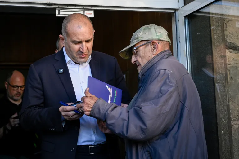 Progressive Bulgaria coalition's leader and former President Radev Rumen talks to a supporter after casting his ballot as he leaves the polling station during Bulgaria's parliamentary elections in Sofia on April 19, 2026.