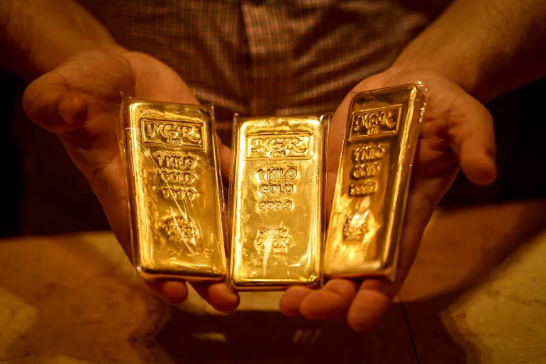 An Emirati gold dealer holds bars of gold in a shop in the Dubai Gold Souk on April 13, 2026. (Photo by FADEL SENNA / AFP)