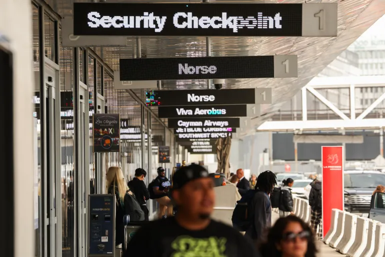 Airline passengers walk beneath signage for Norse Atlantic Airways after the airline canceled flights due to rising fuel costs from Los Angeles International Airport (LAX) in Los Angeles, on April 16, 2026.