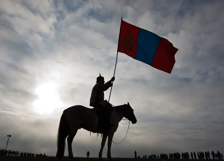 A Mongolian horseman holds a national flag as he waits for children jockeys take part in a horse racing competition during the second day of the Naadam Festival in Khui Doloon Khudag, on the outskirts of Ulan Bator, Mongolia, Thursday, July 12, 2012. Mongolians celebrate the anniversary of Genghis Khan's march to the world conquest with the annual sporting festival featuring traditional Mongolian events such as wrestling, archery, and horse racing. (AP Photo/Andy Wong)