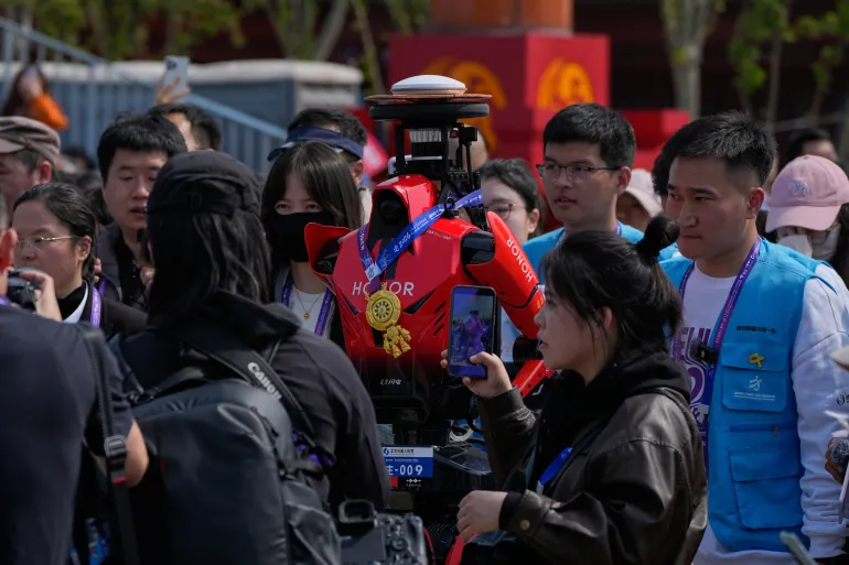 The winner of the humanoid robot half-marathon from Honor is surrounded by journalists after the prize presentation at the Beijing E-Town Half Marathon and Humanoid Robot Half-Marathon on the outskirts of Beijing, Sunday, April. 19, 2026. (AP Photo/Andy Wong)