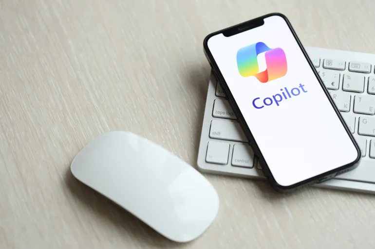 KYIV, UKRAINE - MARCH 17, 2024 Microsoft Copilot logo on iPhone display screen with apple keyboard and mouse on table. Artificial Intelligence engine