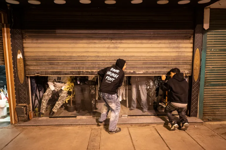epa12857724 Two men close their shop in Cairo, Egypt, 28 March 2026. The Egyptian government has ordered all restaurants, cafes, shopping malls, wedding halls, all sports and community clubs, to shut their doors every day from 9 p.m. onwards, also reduced street lighting levels across the city, as part of the country’s efforts to ration energy due to the ongoing war between Israel and Iran. EPA/MOHAMED HOSSAM