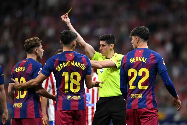 MADRID, SPAIN - APRIL 04: Referee Mateo Busquets Ferrer shows a yellow card to Fermin Lopez of FC Barcelona during the LaLiga EA Sports match between Atletico de Madrid and FC Barcelona at Riyadh Air Metropolitano on April 04, 2026 in Madrid, Spain. (Photo by Denis Doyle/Getty Images)