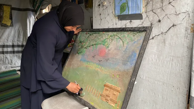 الفنانة أحلام عبد العاطي ترسم لوحة تصور حجم الدمار والخراب الذي أحدثته آلة الحرب الإسرائيلية في غزة / رائد موسى / خان يونس / الجزيرة نت.