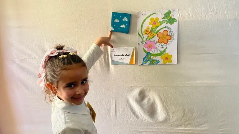 الطفلة النازحة تولين أبو جبارة أصغر فنانة مشاركة في معرض "ما تركته النجاة" بلوحة عنوانها "أنا والألوان" / رائد موسى / مخيم البريج وسط قطاع غزة / الجزيرة نت.