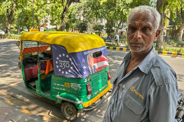Ganesh Kumar stands next to his auto-rickshaw featuring a poster of U.S. President Donald Trump that celebrates "250 Years of America" on the back of his vehicle in New Delhi, India, Wednesday, May 20, 2026. (AP Photo/Piyush Nagpal)