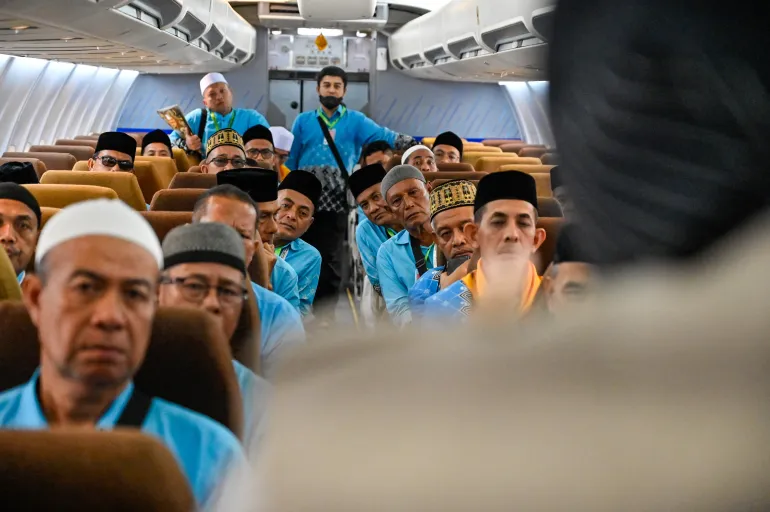Prospective Indonesian hajj pilgrims learn how to use life jackets from cabin crew aboard a retired Boeing 737 during a pre-departure safety training session at the hajj embarkation centre in Banda Aceh on May 14, 2026. (Photo by CHAIDEER MAHYUDDIN / AFP)