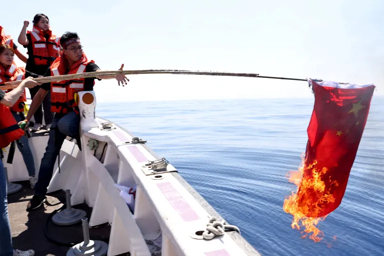 Members of the pro-independence Taiwan Statebuilding Party burn a Chinese flag on boat trip in the Taiwan Strait, in Kaohsiung