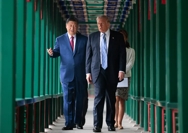US President Donald Trump (C) walks with China’s President Xi Jinping (L) at Zhongnanhai Garden in Beijing on May 15, 2026. (Photo by Evan Vucci / POOL / AFP)