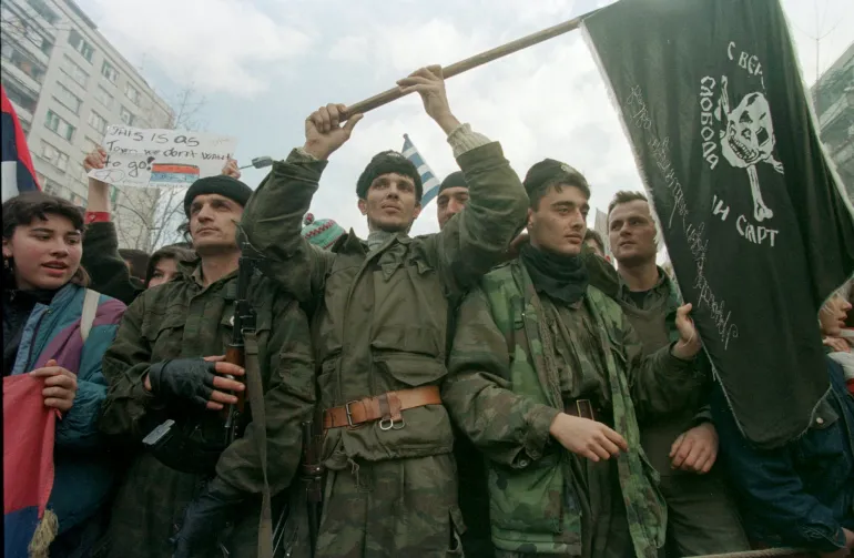 Serb militia members hold a black flag with a skull and cross bones during a demonstration against the Dayton peace agreement in the Serb-held Sarajevo neighborhood of Grbavica Thursday, December 7, 1995. Five thousand Serbs in Grbavica protested the peace accord that would give their district to their enemies across the river. Nobody knows if they'll really fight, run, or give in to the approaching NATO army aiming to enforce the peace. (AP Photo/Enric F.Marti)