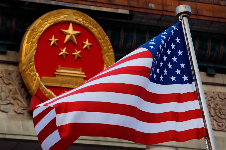 FILE - An American flag is flown next to the Chinese national emblem during a welcome ceremony for visiting U.S. President Donald Trump outside the Great Hall of the People in Beijing on Nov. 9, 2017. (AP Photo/Andy Wong, File)