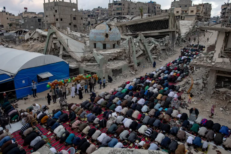 epa12996589 Displaced Palestinians perform Eid al-Adha prayers beside the ruins of Al-Huda Mosque in Khan Younis, southern Gaza Strip, 27 May 2026. Eid al-Adha, also known as the Feast of Sacrifice, coincides with the annual Hajj pilgrimage to Mecca and is traditionally marked by the sacrifice of livestock and the distribution of meat among family, friends and those in need. EPA/HAITHAM IMAD