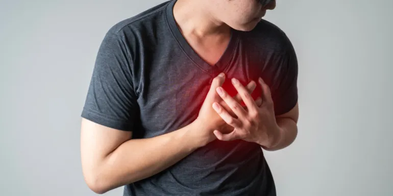 heart disease concept. man pressing on chest with painful expression. severe heartache and having heart attack or painful cramps.
