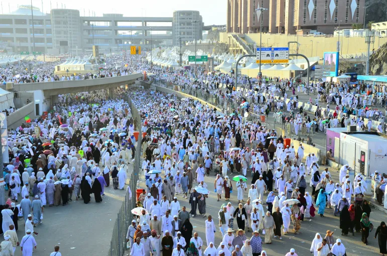 Mecca, Saudi Arabia - October 16, 2013: A group of Hajj pilgrims walk in the city of Mina to perform the ritual of stoning the devils at Jamarat. Around 2 million people perform the Hajj every year.