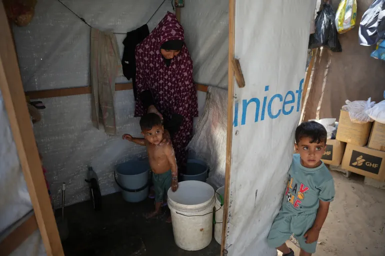 Iman Mansour bathes her son, Mohamed Shaban, in a makeshift bathroom beside her family’s tent in Khan Younis, southern Gaza Strip, Wednesday, June 3, 2026. (AP Photo/Abdel Kareem Hana)