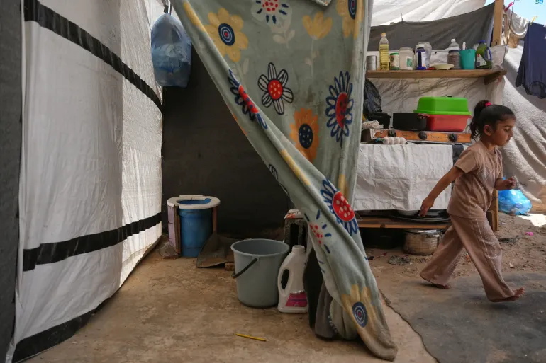 Wateen Darwish walks past her family’s makeshift toilet at a camp for displaced Palestinians in Khan Younis, southern Gaza Strip, Wednesday, June 3, 2026. (AP Photo/Abdel Kareem Hana)