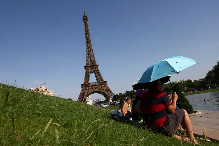 People use umbrellas to shade from the sun near the Trocadero fountain in front of the Eiffel Tower as temperatures rise in Paris during a heatwave affecting a large part of France, June 23, 2026. REUTERS/Abdul Saboor