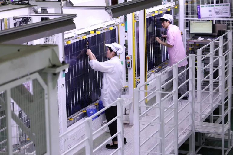 Workers produce a batch of solar photovoltaic modules for export to Germany at a new energy company in Lianyungang, in China's eastern Jiangsu province on June 8, 2026. (Photo by CN-STR / AFP) / CHINA OUT