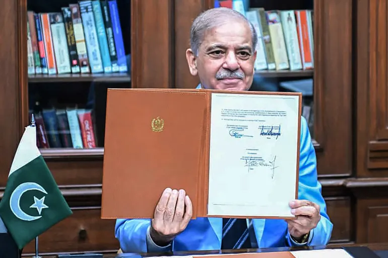 This handout photograph taken and released by Pakistan's Prime Minister's Office on June 18, 2026 shows Pakistan's Prime Minister Shehbaz Sharif holding the memorandum of understanding after signing it as a peace mediator to end the Middle East war, in Islamabad.