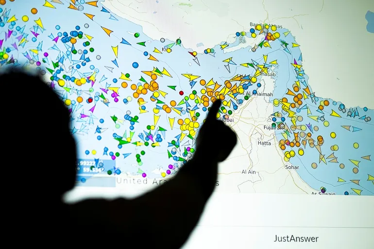 (FILES) A photo illustration taken in Nicosia on May 4, 2026, shows a person in front of a large screen displaying vessel movements in the Strait of Hormuz on a ship-tracking website.